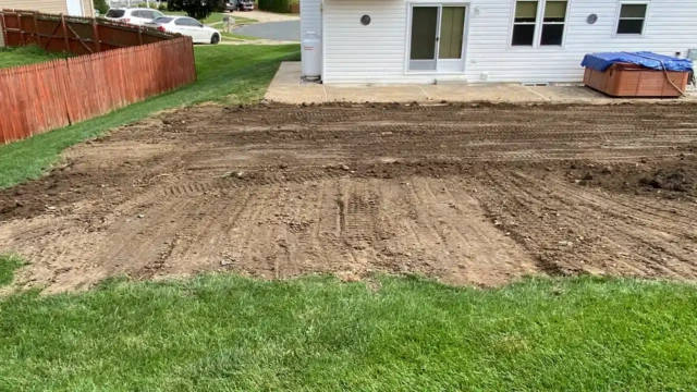 Here we are leveling and grading the area to make sure its stable to avoid future issues. The backyard has been filled in and leveled with fresh soil, leaving visible tracks from heavy machinery. The area where the pool used to be is now a dirt patch ready for grass or landscaping.